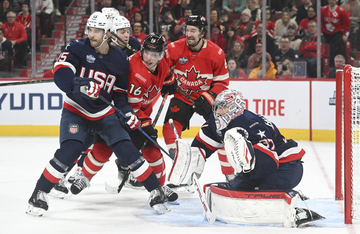Canada's Mitch Marner (16) and Mark Stone (61) move in on United States goaltender Connor Helle ...
