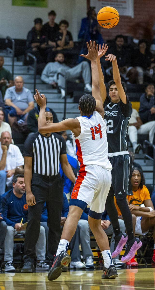 Desert Pines guard Aaron McMorran (22) shoots a three-point basket over the hand of Bishop Gorm ...