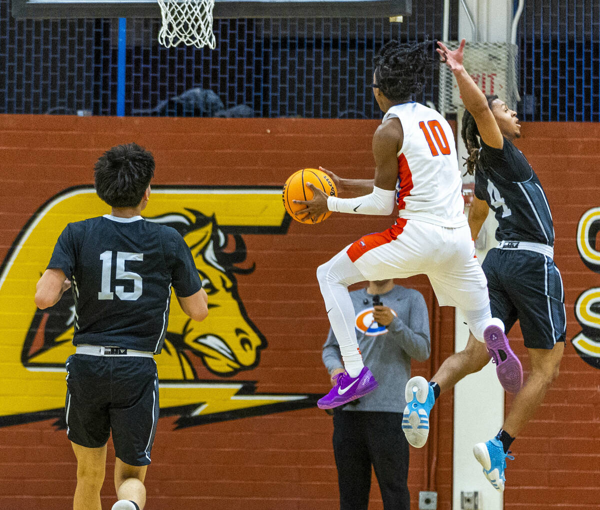 Bishop Gorman guard Nick Jefferson (10) elevates behind Desert Pines guard Prince Davis (4) for ...