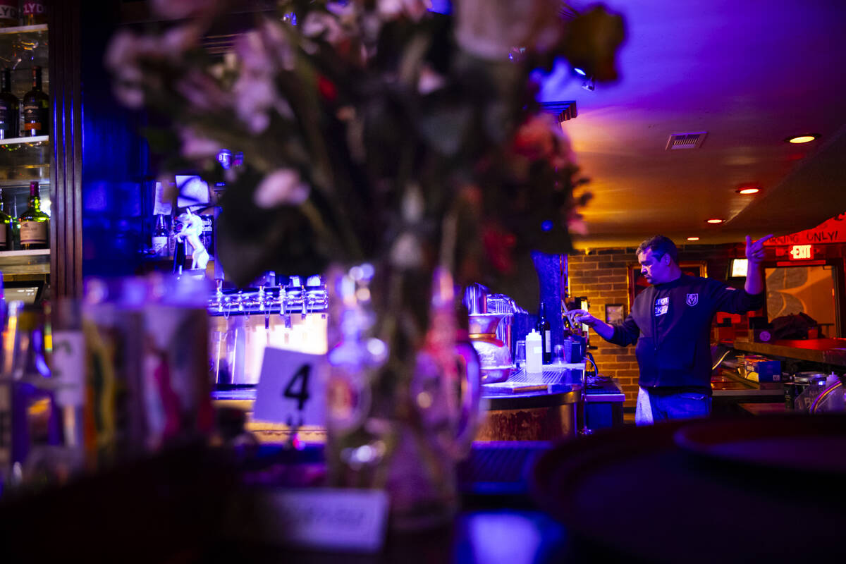 Bartender Dean Howard prepares a drink as floral arrangements and candles from nearby businesse ...