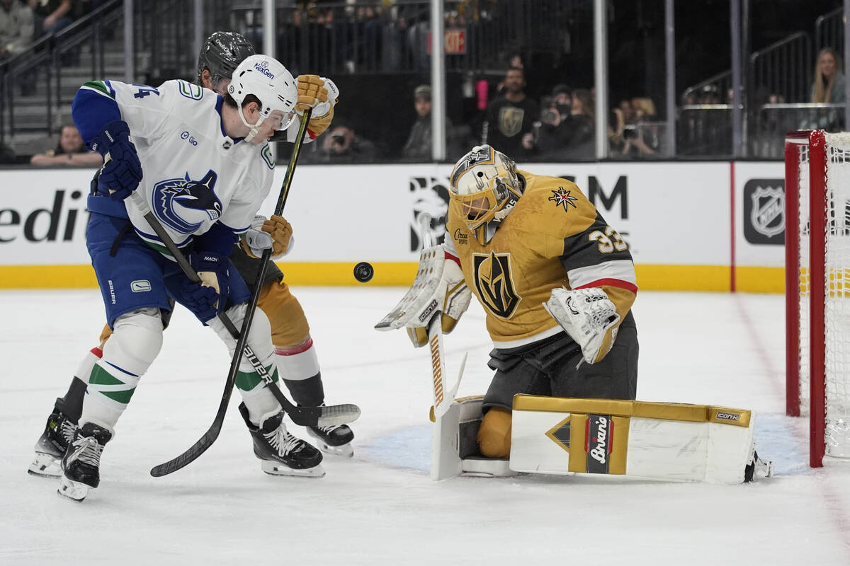 Vegas Golden Knights goaltender Adin Hill (33) blocks a shot beside Vancouver Canucks left wing ...