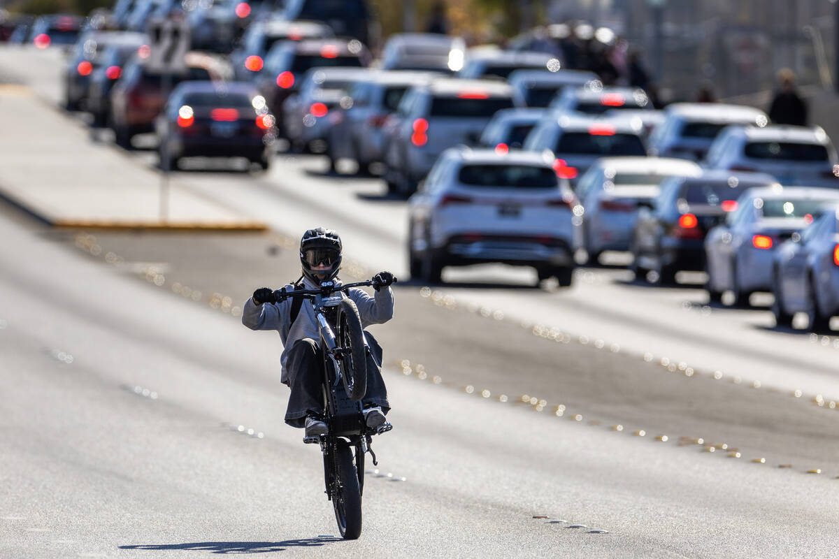 A student riding an e-dirt bike pops a wheelie on Coronado Center Drive near Coronado High Scho ...