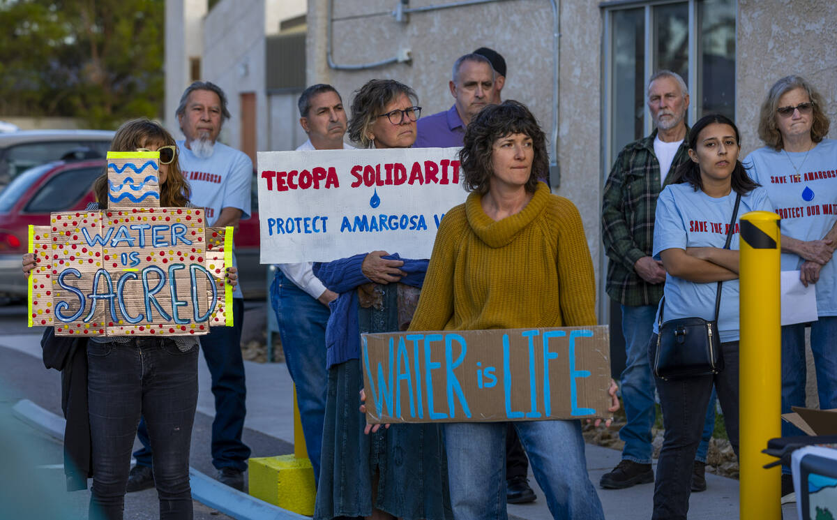 Attendees hold signs as they gather outside the Amargosa Valley Community Center for a rally be ...