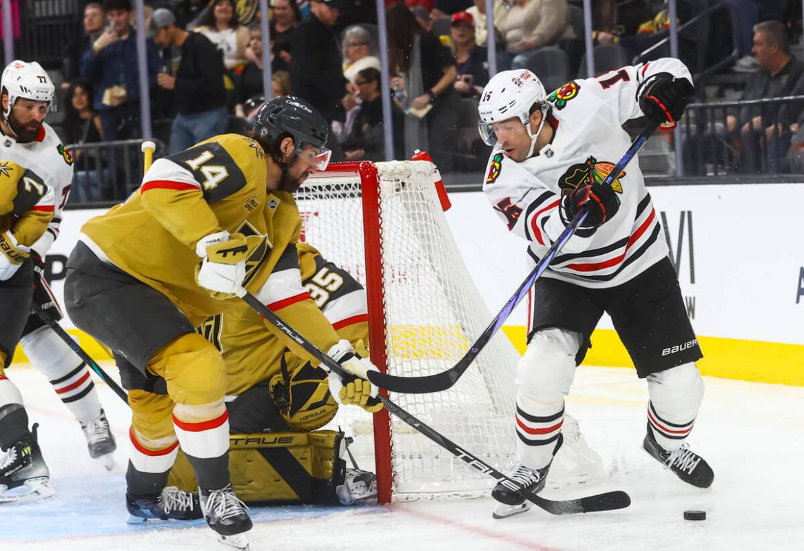 Golden Knights defenseman Nicolas Hague (14) gets the puck away from Chicago Blackhawks center ...