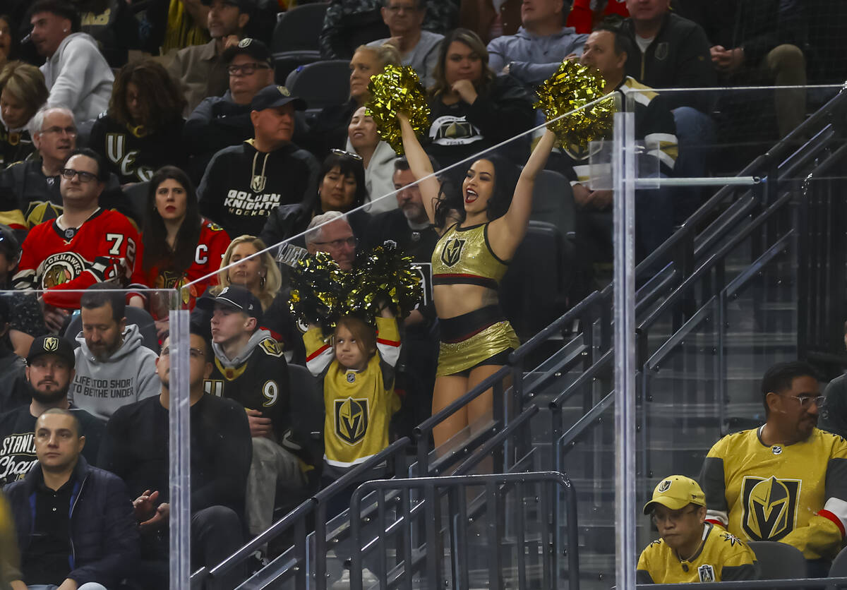 A young Golden Knights fan cheers with a member of the Vegas Vivas during the second period of ...