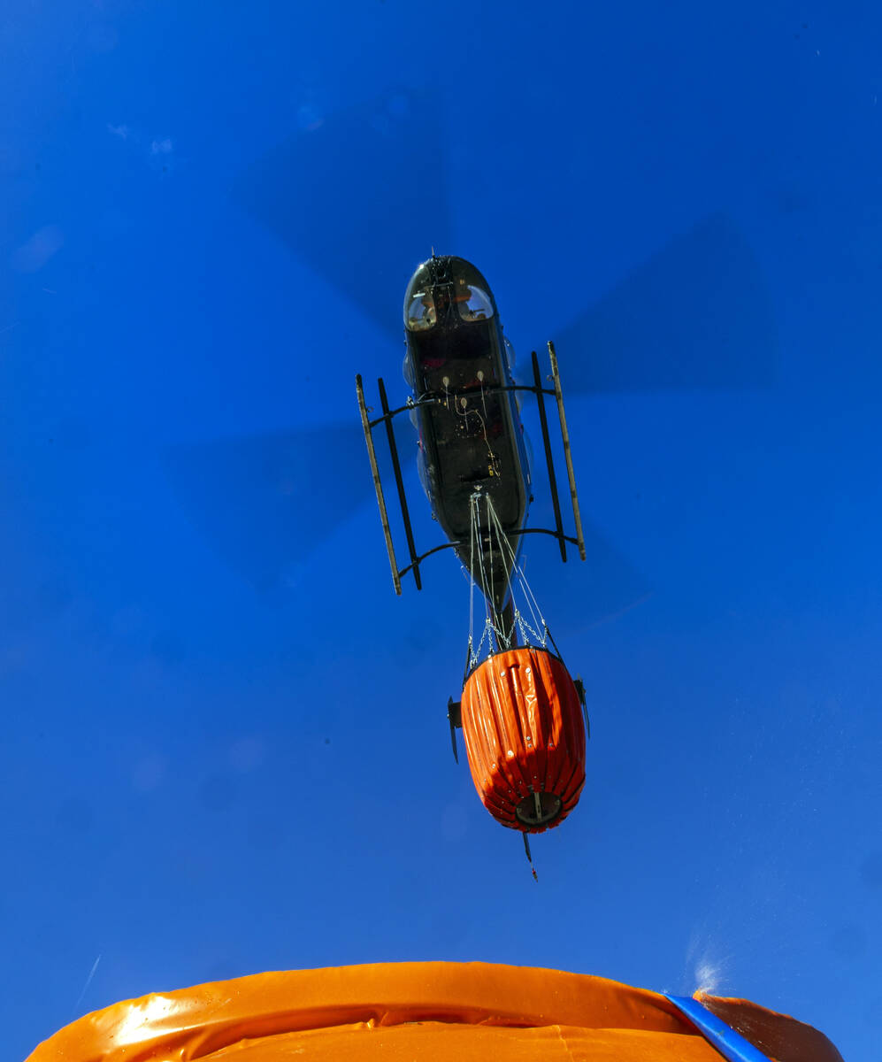 A helicopter returns to a portable water tank with en empty Bambi Bucket to refill on Friday, F ...