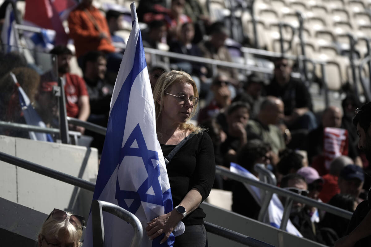 A mourner holds the Israeli flag at a public memorial ceremony for slain hostage Tsachi Idan, a ...