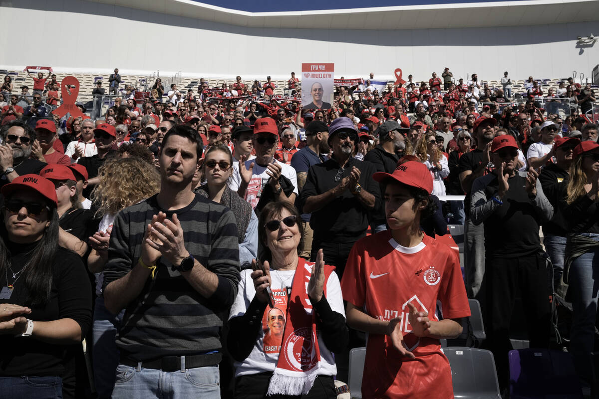 Dvora Idan, center, and her family applaud at a public memorial ceremony for her son, slain hos ...