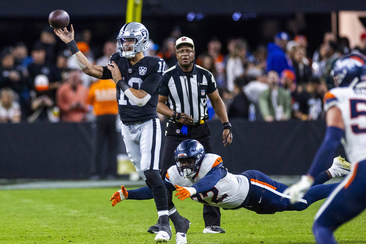 Raiders quarterback Desmond Ridder (10) gets off pass with pressure from Denver Broncos linebac ...