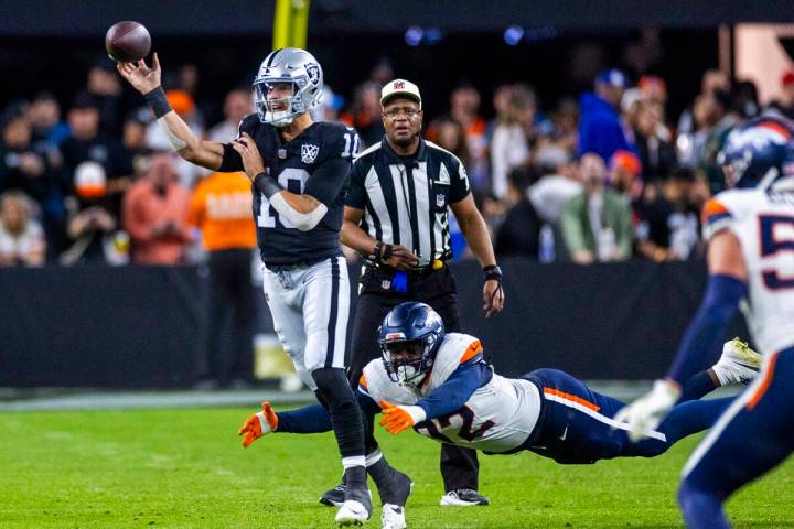 Raiders quarterback Desmond Ridder (10) gets off pass with pressure from Denver Broncos linebac ...