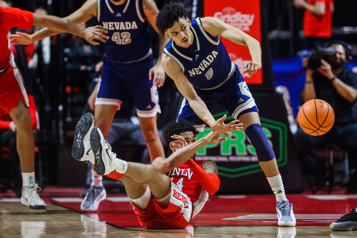 Rebels guard Jailen Bedford (14) passes the ball to a teammate after falling during an NCAA men ...