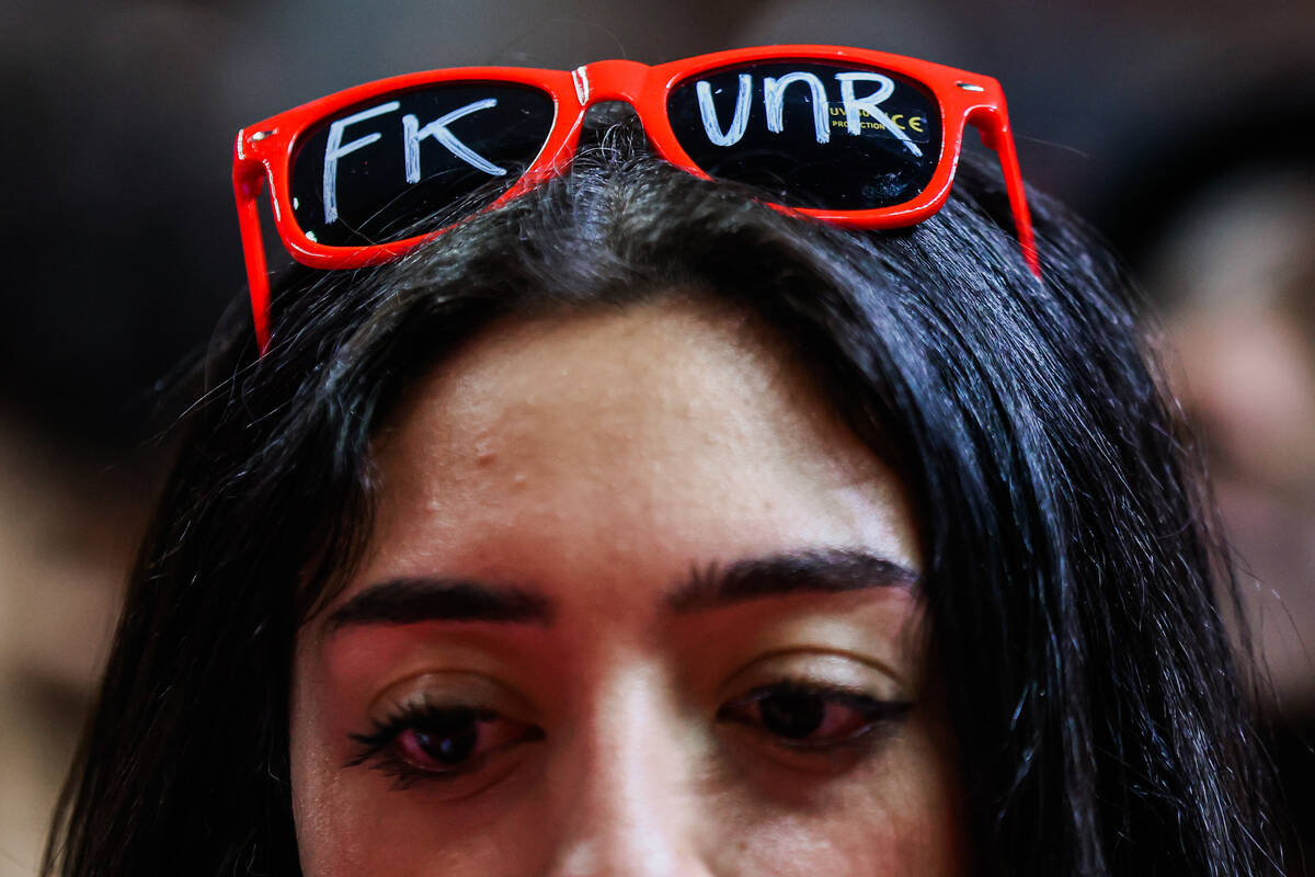 A Rebels fan props sunglasses on their head during an NCAA men’s basketball game between ...