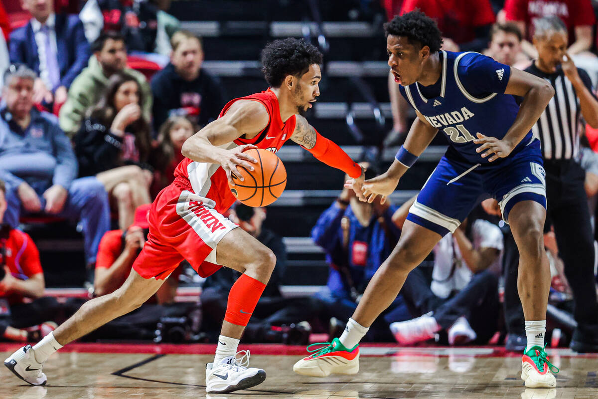 Rebels guard Jailen Bedford (14) dribbles the ball as UNR Wolf Pack forward Justin McBride (21) ...