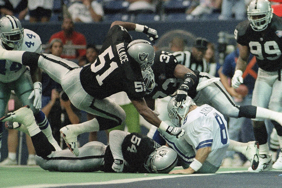 Dallas Cowboys quarterback Troy Aikman (11) is hit by Los Angeles Raiders defenders Aaron Walla ...