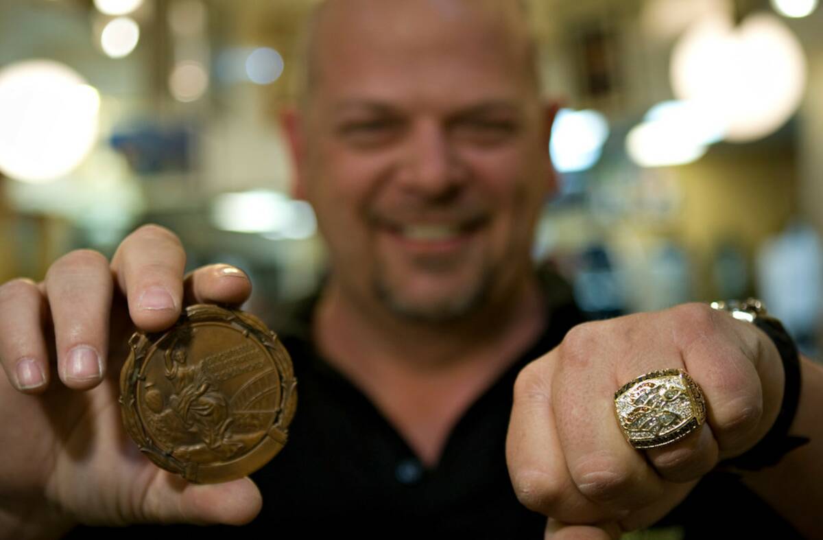 Rick Harrison holds up a bronze medal from the 1960 Rome Olympics and 1998 Broncos Super Bowl R ...