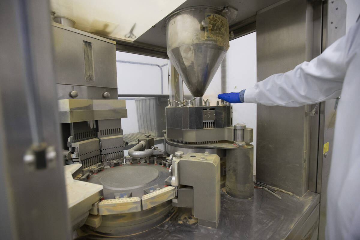 James Smith, VP of operations at Nature’s Lab, shows a machine that presses together cap ...