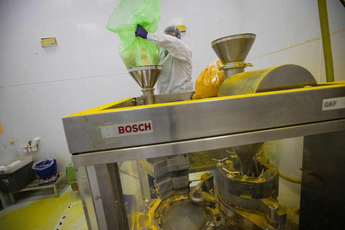 An employee loads empty capsules into a press machine to make turmeric supplements at the Natur ...