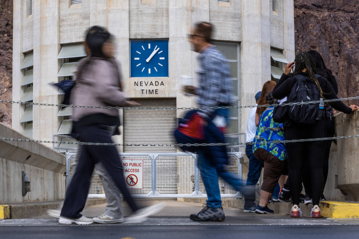 Visitors pass by a clock which shows Nevada time at the Hoover Dam as efforts to get rid of Day ...