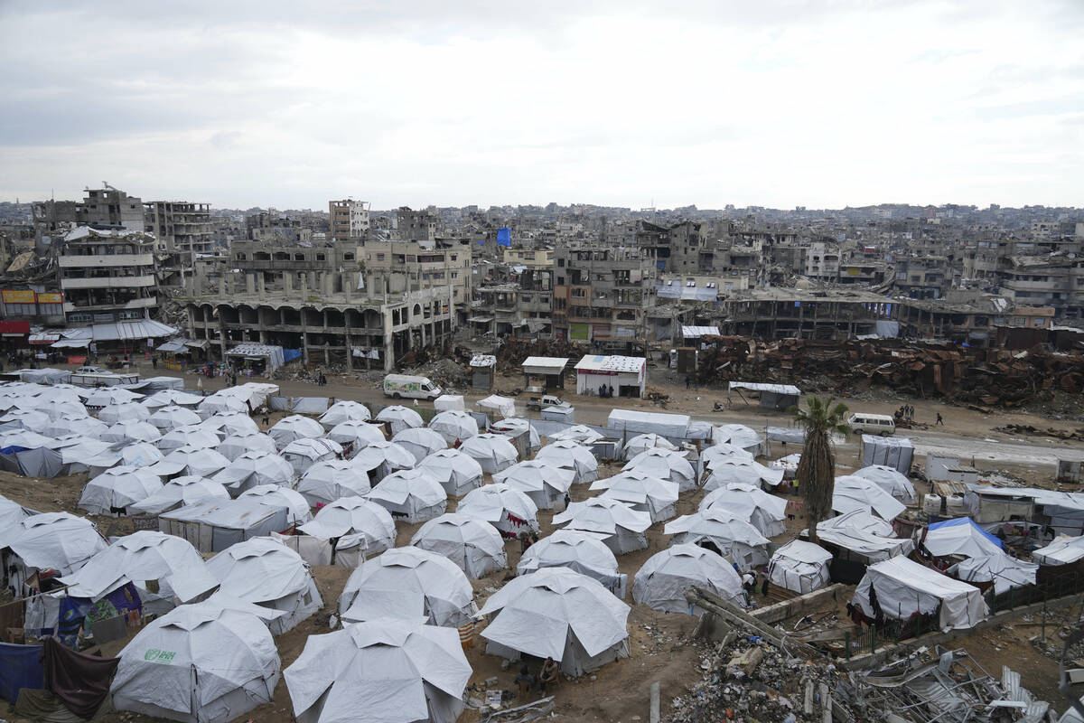 A sprawling tent camp for displaced Palestinians sits adjacent to destroyed homes and buildings ...