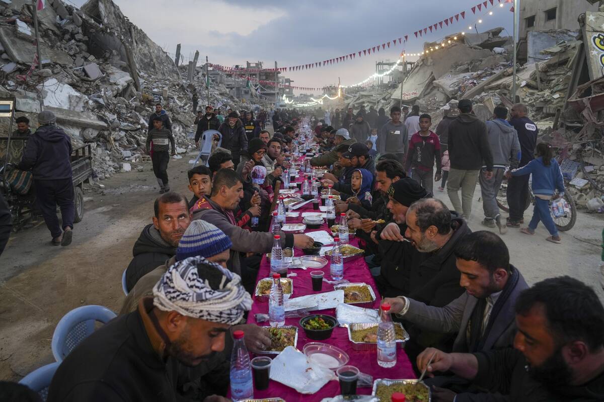 Palestinians sit at a large table surrounded by the rubble of destroyed homes and buildings as ...