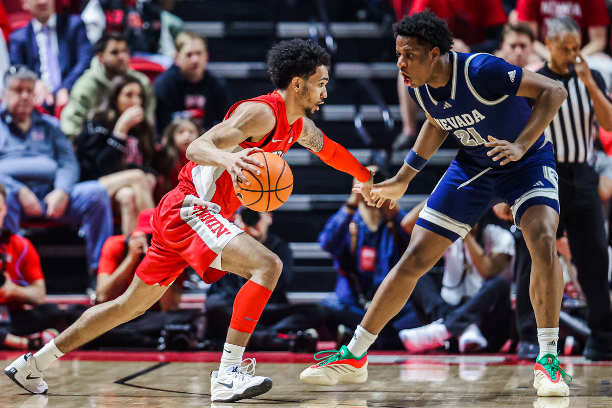 Rebels guard Jailen Bedford (14) dribbles the ball as UNR Wolf Pack forward Justin McBride (21) ...