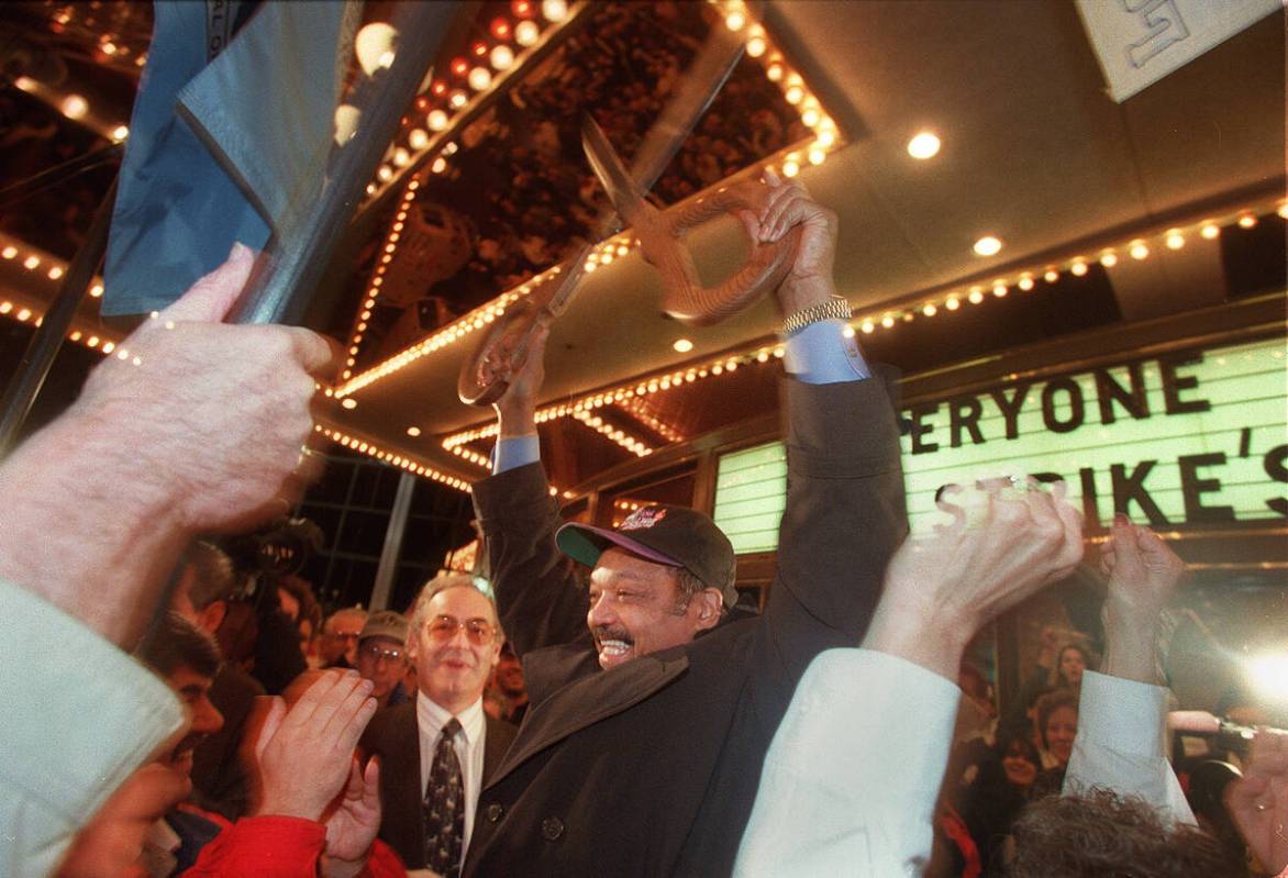 Jesse Jackson holds up the scissors he and new Frontier owner Phil Ruffin, left, used to cut a ...