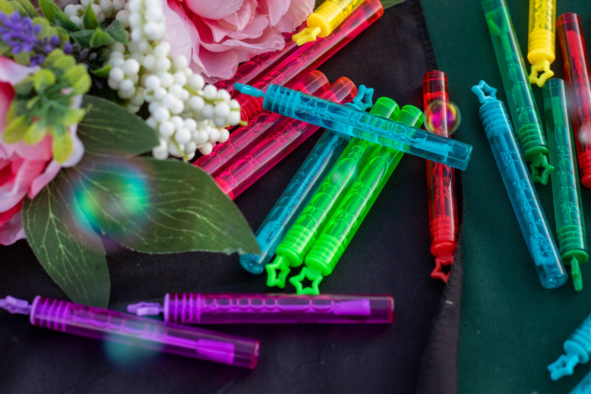 Colorful bottles of bubbles sit on a table with faux flowers, set up for a vigil and bubble rel ...