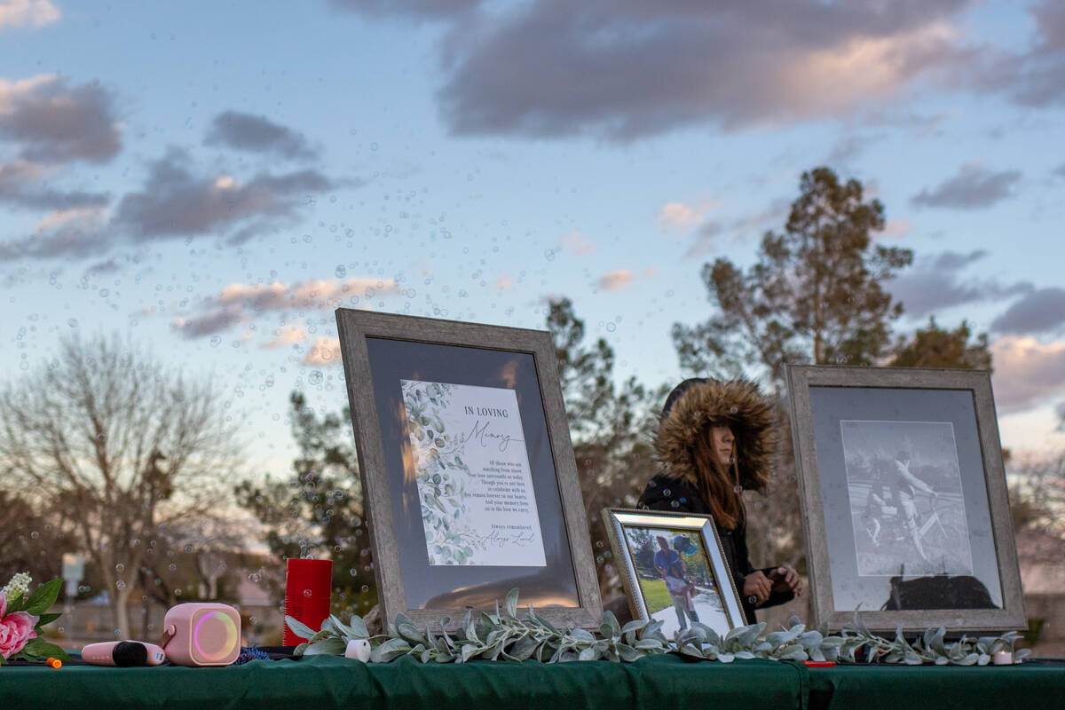 Memorial photos sit on a table set up by friends and family at a vigil and bubble release cerem ...
