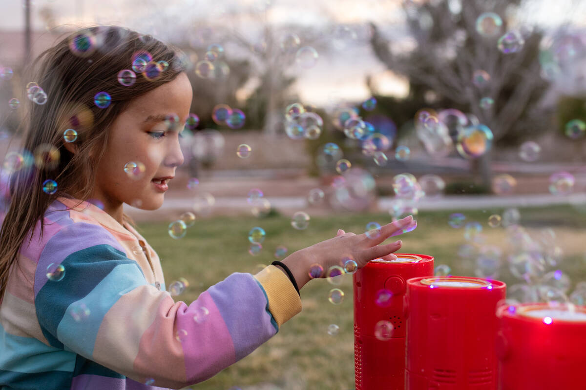 Yoyo Wang, 6, touches the machines producing bubbles at a vigil and bubble release ceremony for ...