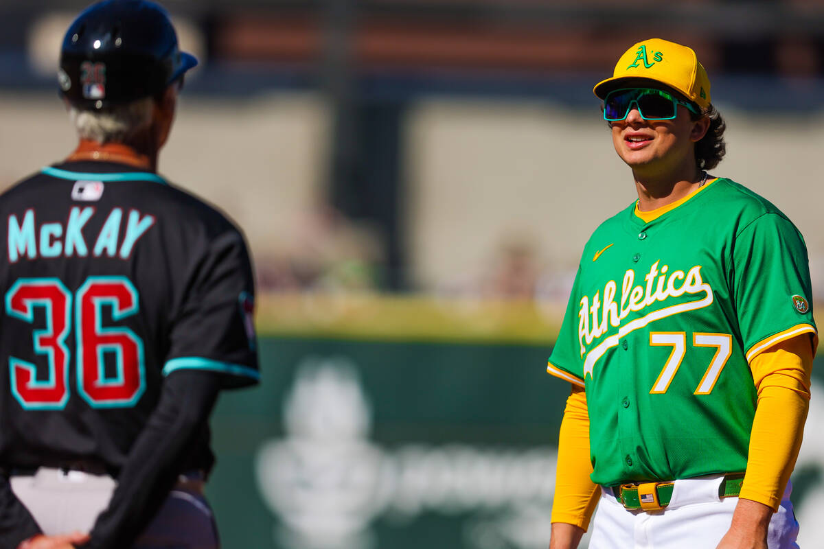 Athletics infielder Nick Kurtz (77) speaks to Arizona Diamondbacks first base coach Dave McKay ...
