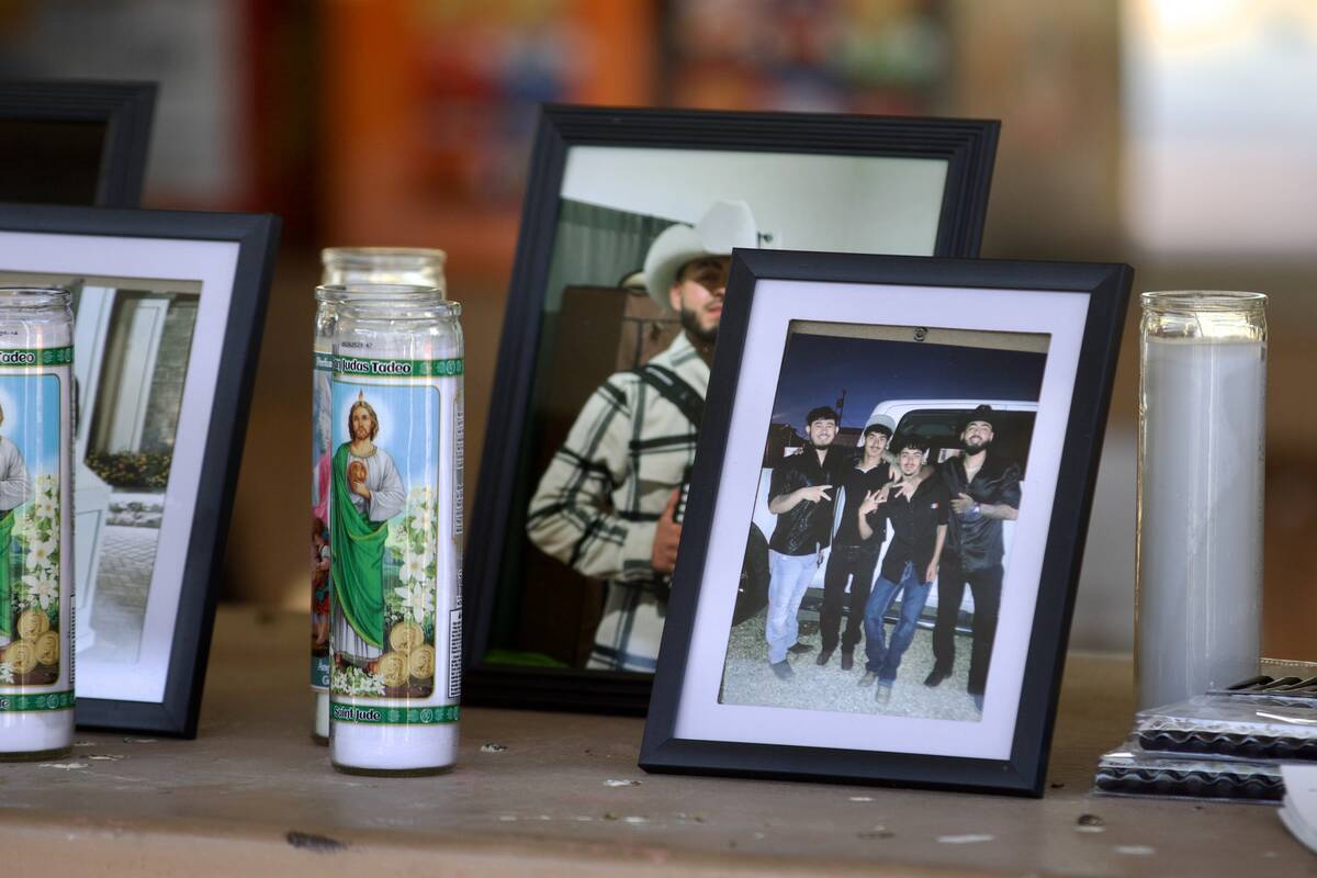 Prayer candles and photos sit on a picnic table during a candlelight vigil and balloon release ...