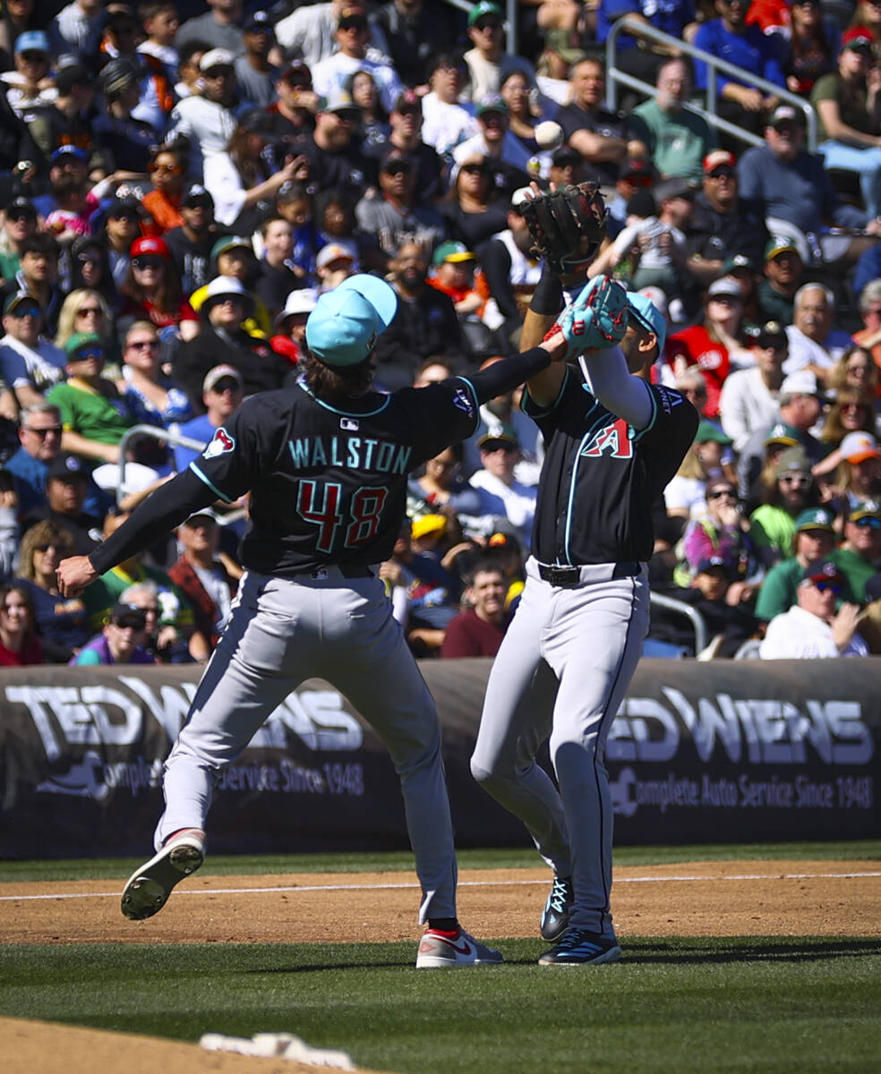 Arizona Diamondbacks shortstop Jordan Lawlar, right, catches a fly ball as pitcher Blake Walsto ...