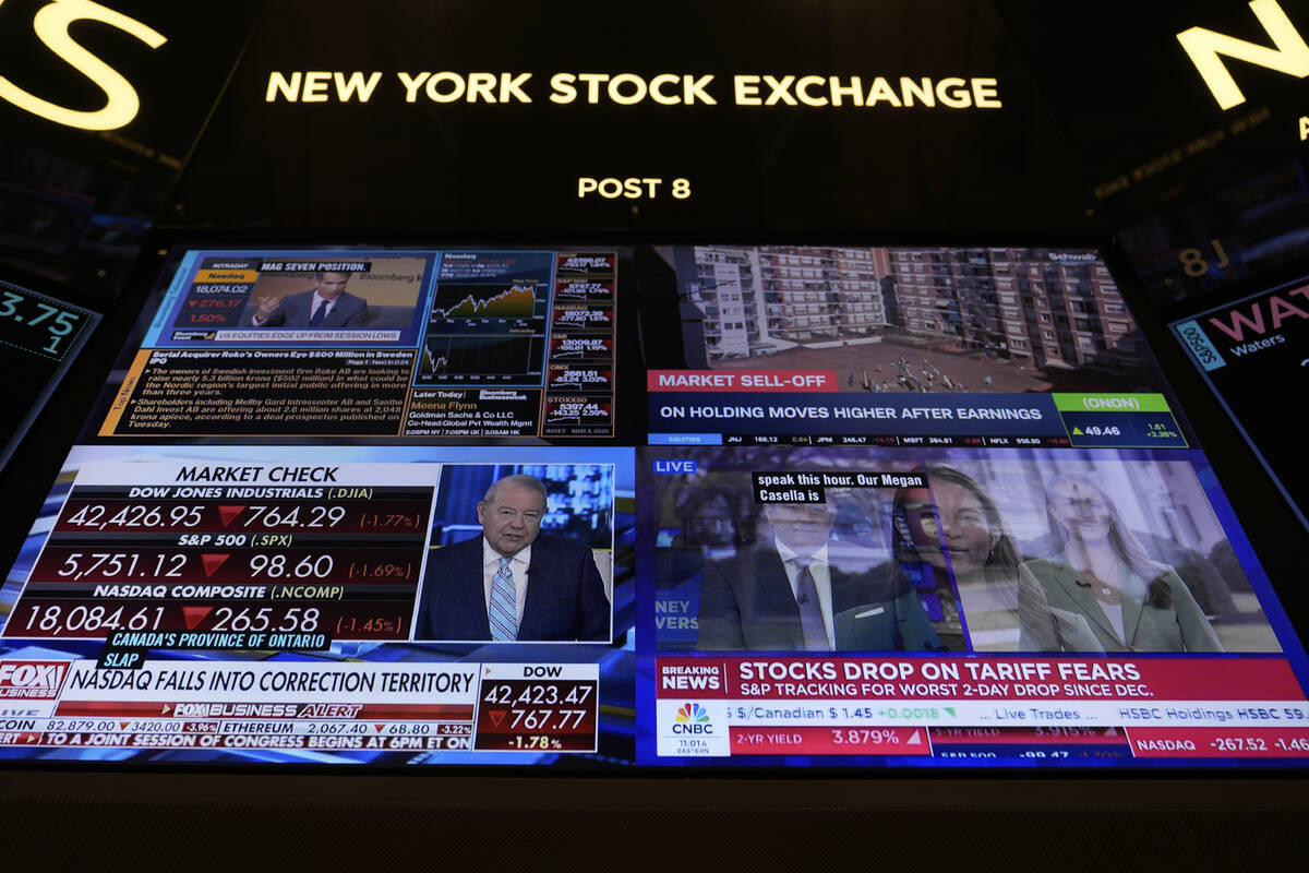 Financial news is displayed as people work on the floor at the New York Stock Exchange in New Y ...