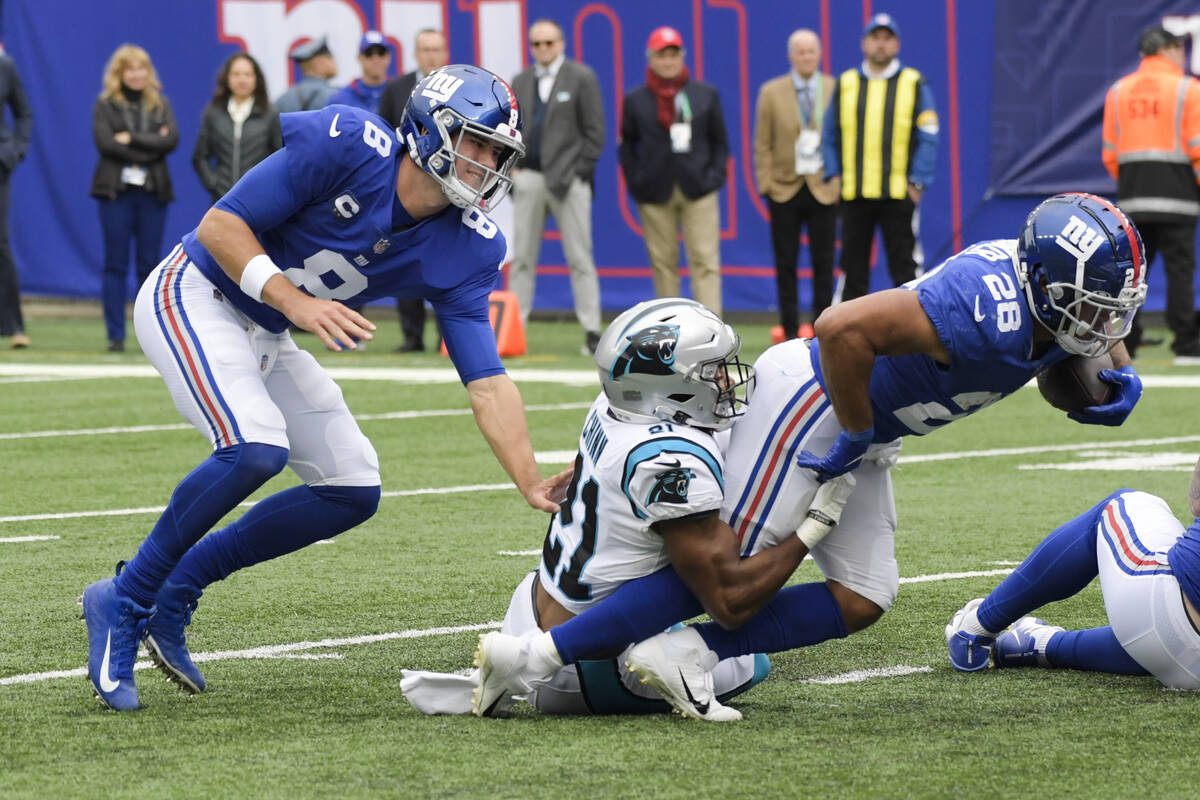 New York Giants quarterback Daniel Jones (8) watches as Carolina Panthers' Jeremy Chinn (21) ta ...
