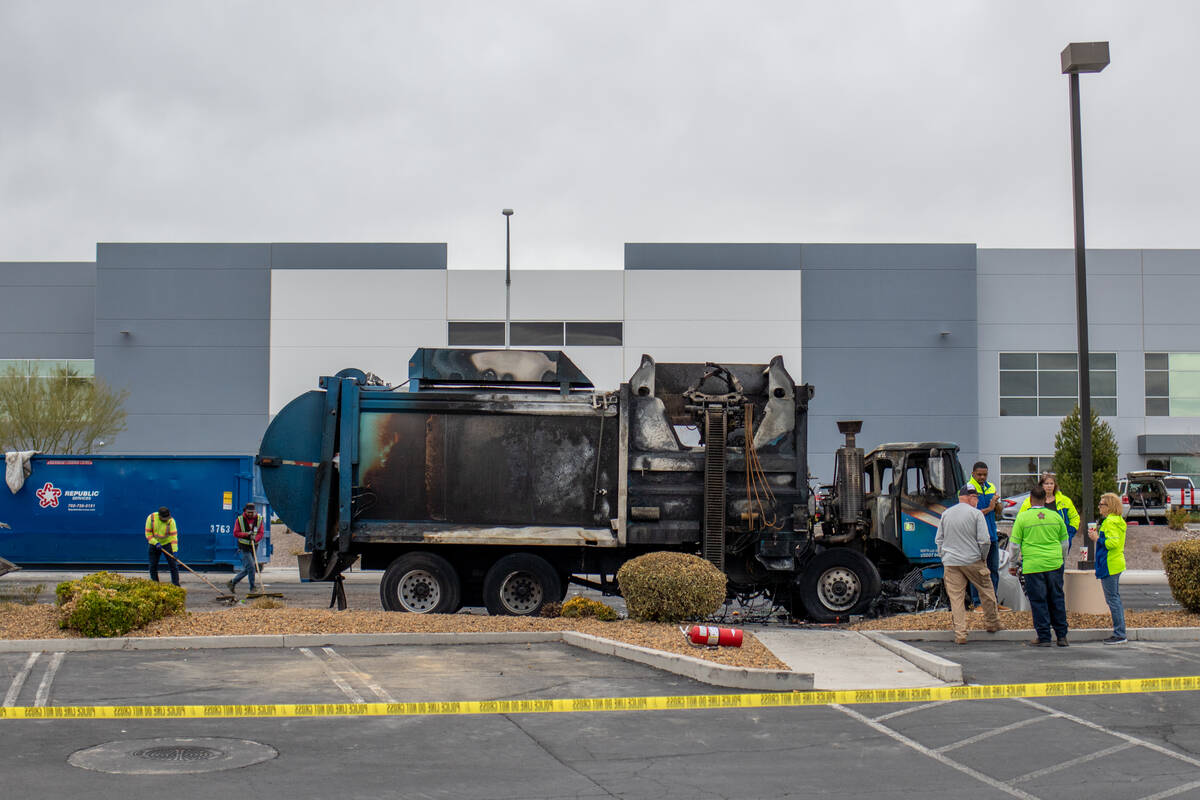 Clean-up crews start to sweep debris off the road at the site of a fatal car crash along a stre ...