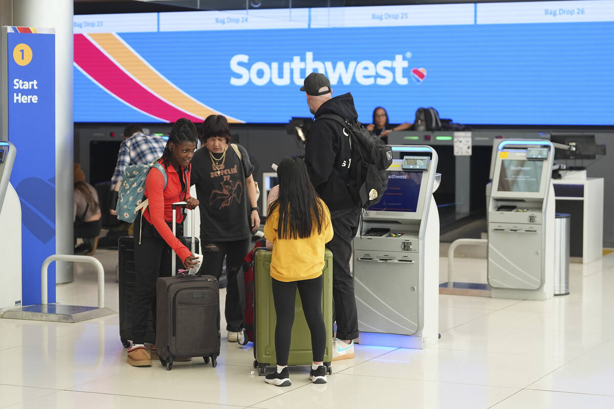 Passengers check in at a kiosk at the tocketing counter for Southwest Airlines in Denver Intern ...