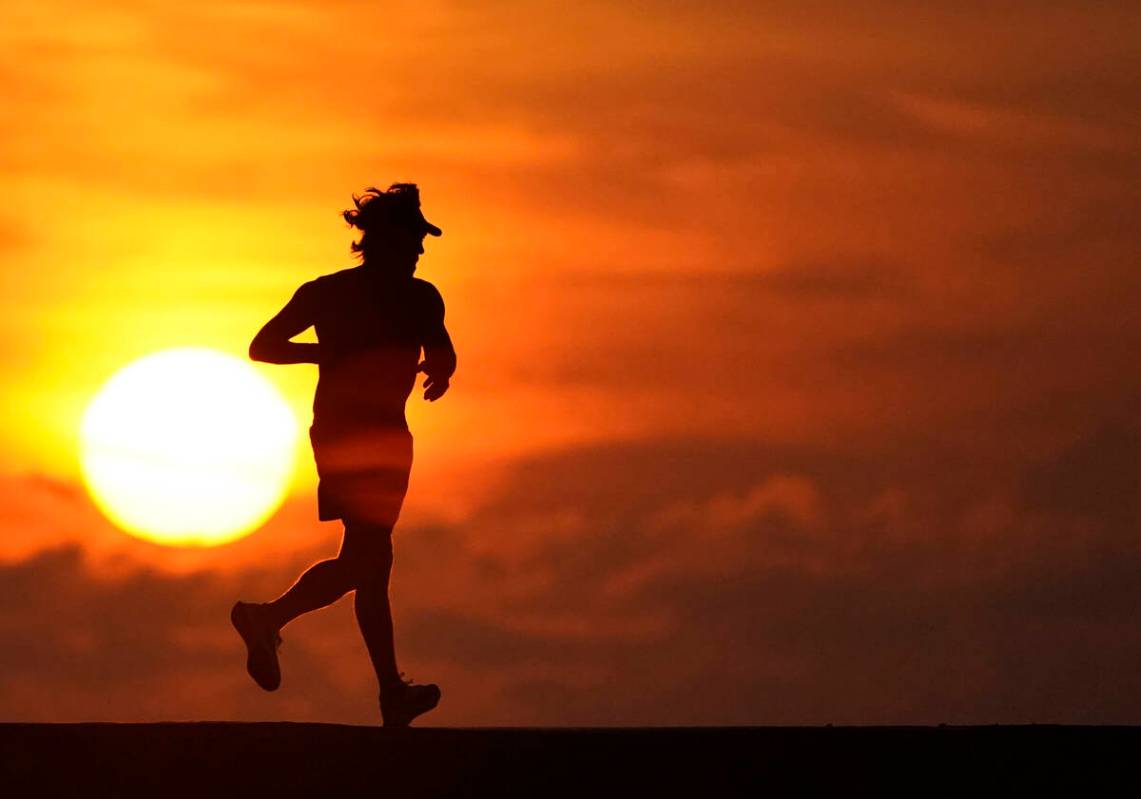 FILE - A jogger is silhouetted while running on a jetty at sunrise over the Atlantic Ocean in B ...