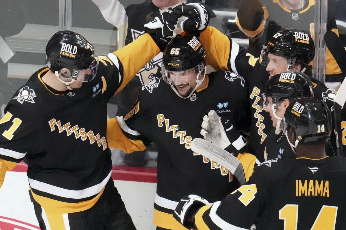 Pittsburgh Penguins' Erik Karlsson (65) celebrates with teammates after getting the game-winnin ...