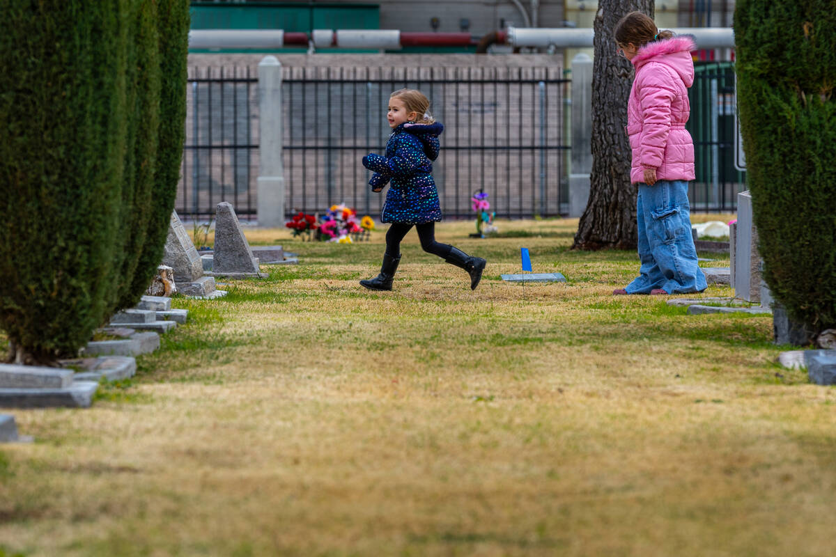 Mimi Bumgarner, 4, and sister Etta, 10, ensure each flat grave marker has a stone as the local ...