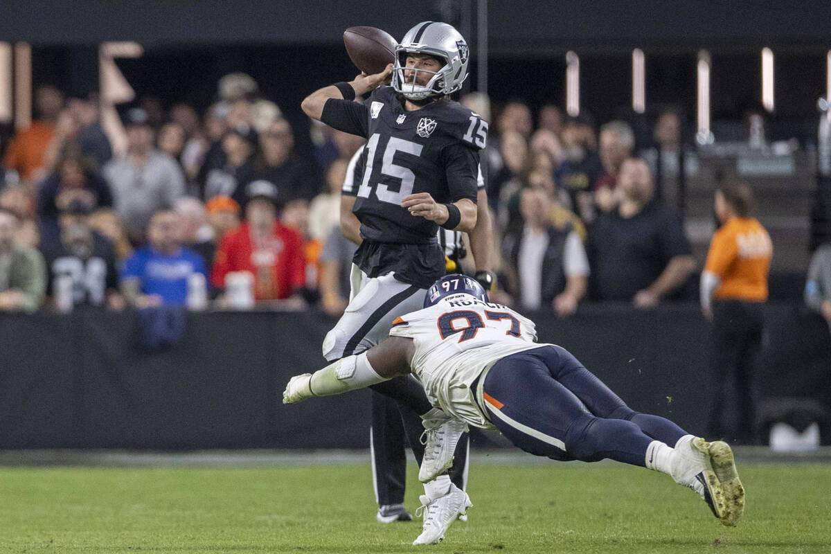 Raiders quarterback Gardner Minshew (15) throws under pressure from Denver Broncos defensive ta ...