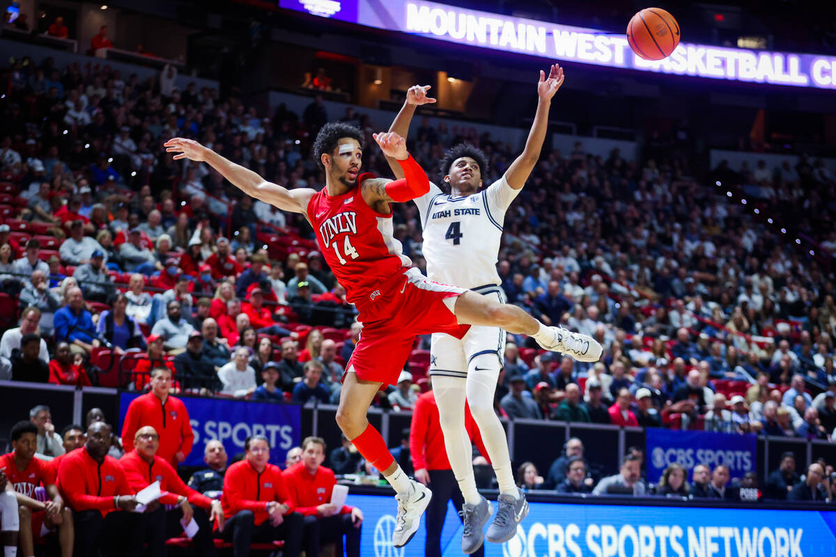 Rebels guard Jailen Bedford (14) and Utah State Aggies guard Ian Martinez (4) leap up for posse ...