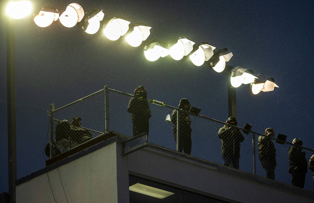 Spotters attempt to stay dry on the rooftop as rain begins during the NASCAR Craftsman Truck Se ...