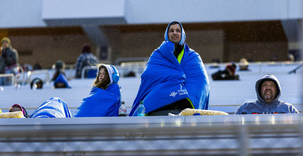 Fans attempt to stay dry in the stands as rain begins during the NASCAR Craftsman Truck Series ...