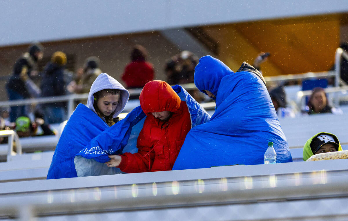 Fans attempt to stay dry in the stands as rain begins during the NASCAR Craftsman Truck Series ...