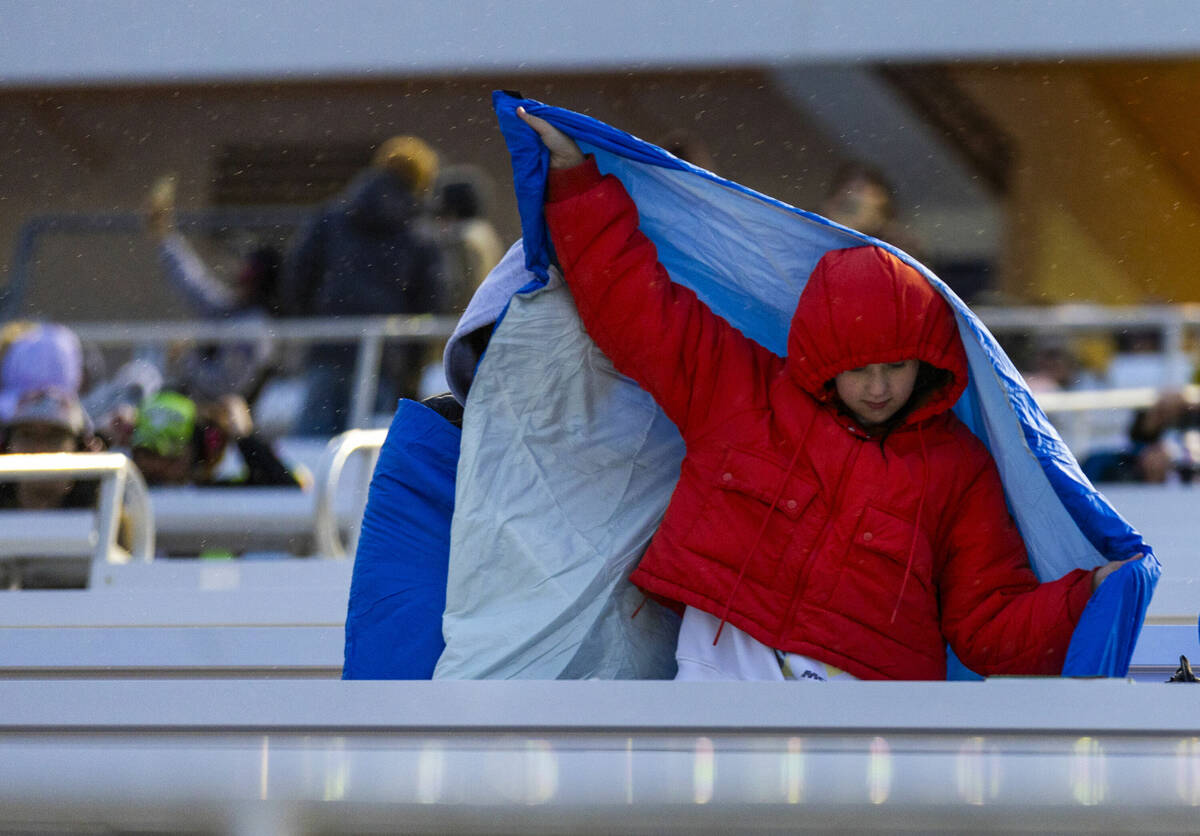 Fans attempt to stay dry in the stands as rain begins during the NASCAR Craftsman Truck Series ...