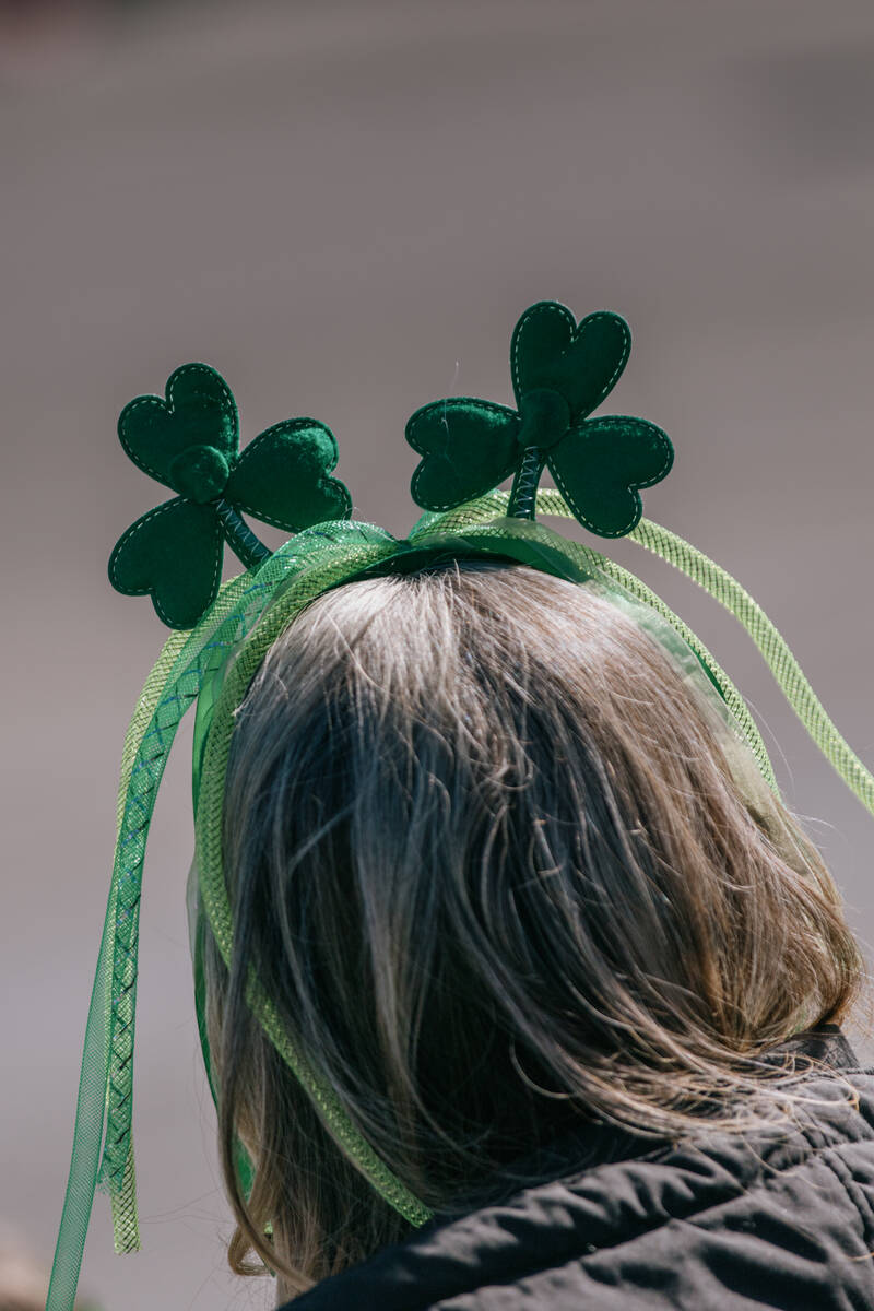An attendee sports a clover-shaped headband while watching the annual St. Patrick’s Day ...