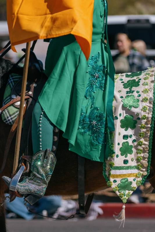 A parade participant riding a horse wears sparkling boots and green attire while holding the Ir ...