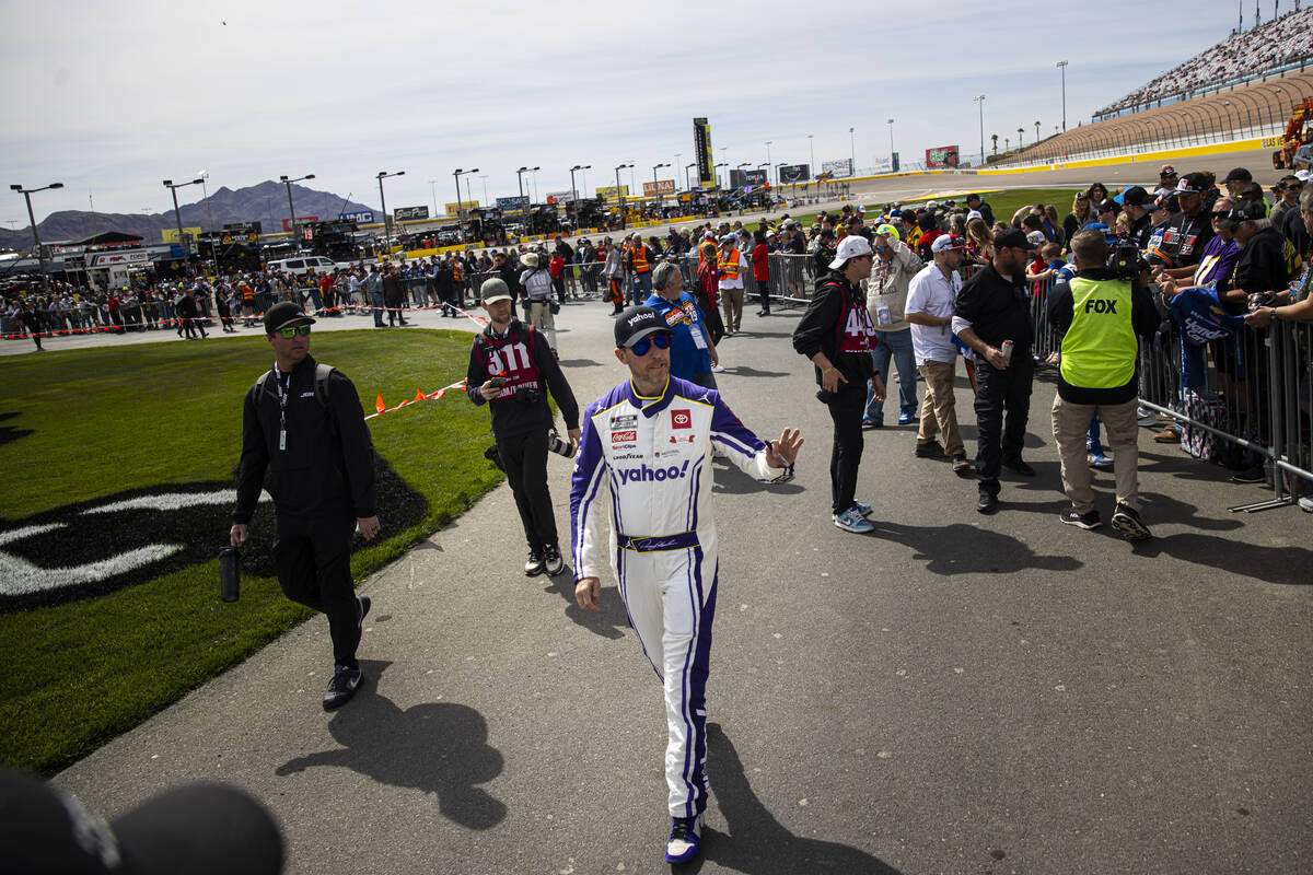 Driver Denny Hamlin makes his way to driver introductions before the start of the Pennzoil 400 ...