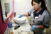 Housecleaning staff member Jacque Iribe collects used soap products while cleaning a hotel room ...