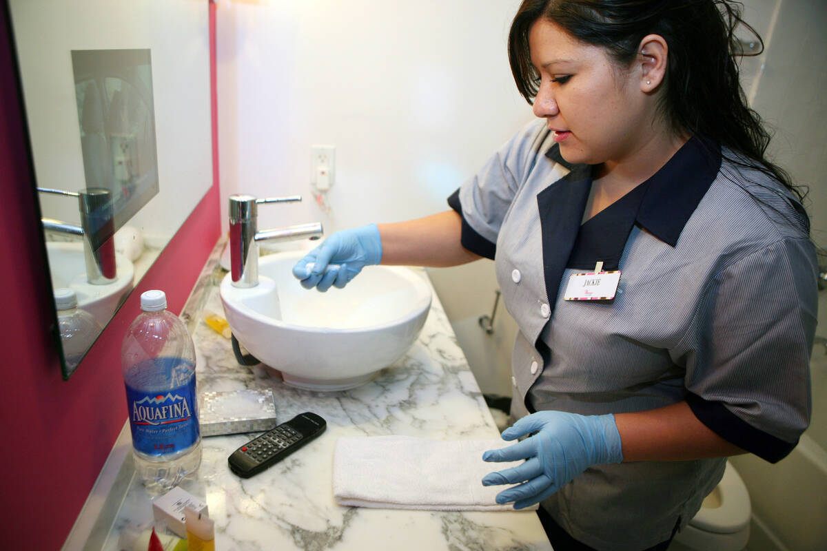 Housecleaning staff member Jacque Iribe collects used soap products while cleaning a hotel room ...